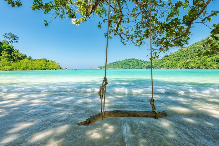 Beach swing overlooking turquoise ocean and green islands