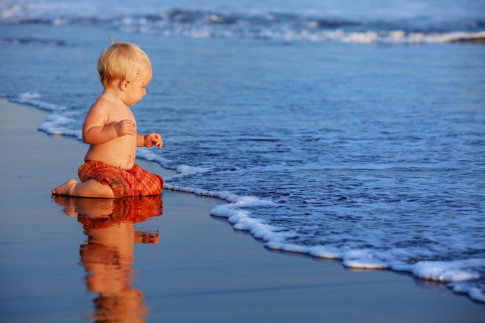 Baby boy playing on the beach by the ocean