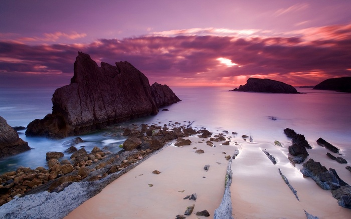 Rocky coastline at sunset with purple clouds