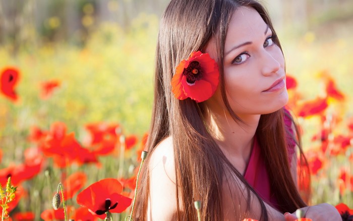 Brown-haired woman with poppy in field of poppies