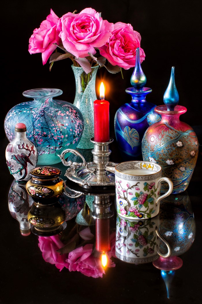 Still-life with roses, candle, and ornate bottles