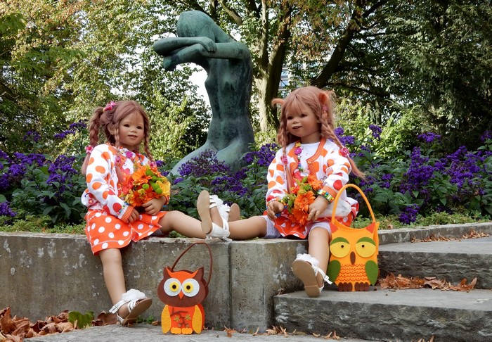Two dolls in a park with a sculpture