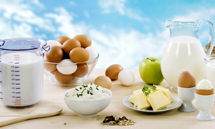 Dairy products, eggs, apple, and muesli on a wooden table
