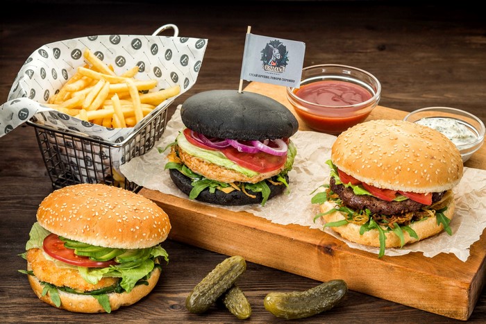 Three burgers with fries and dipping sauces