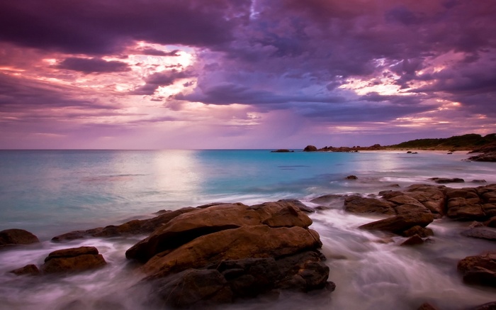 Rocky coastline with purple clouds at sunset