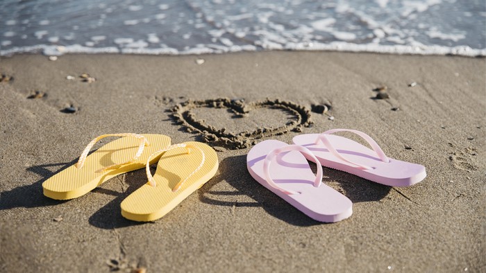 Beach with heart drawn in sand and flip-flops
