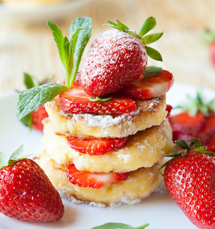 Stack of pancakes with strawberries and powdered sugar