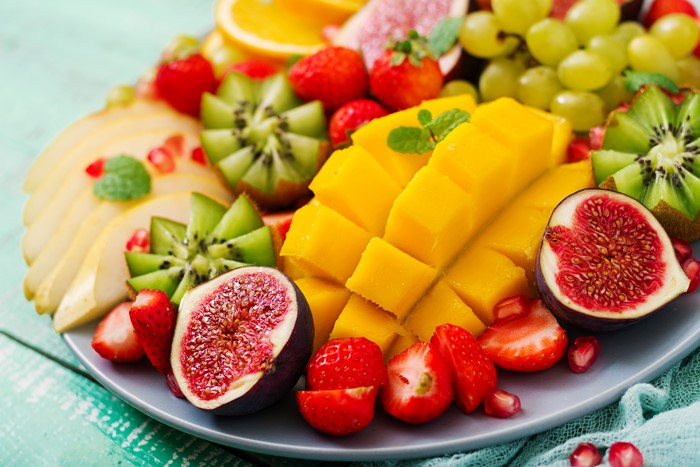Fruit platter with mango, kiwi, figs, strawberries, grapes, and oranges