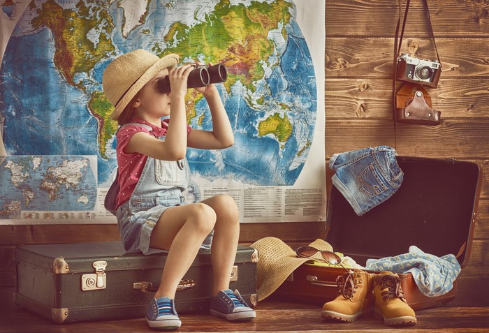 Little girl with binoculars and suitcase
