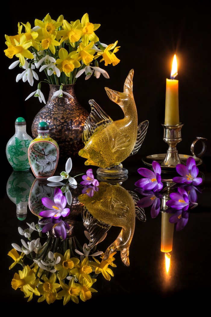 Still-life with daffodils, snowdrops, crocus, glass fish, and candle