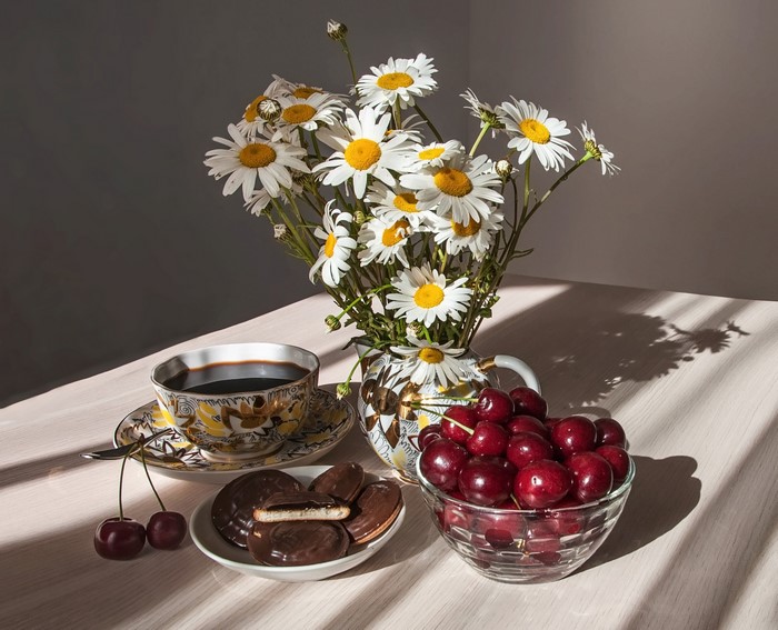 Still-life with camomiles, coffee, cherries, cookies, and cup