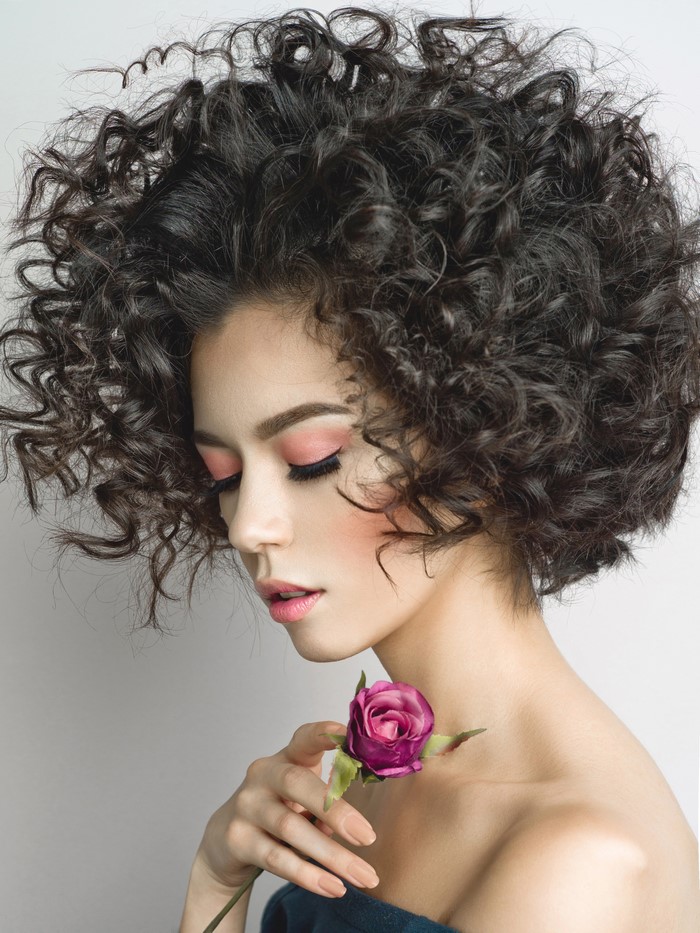 Brunette girl with curly hair holding a rose