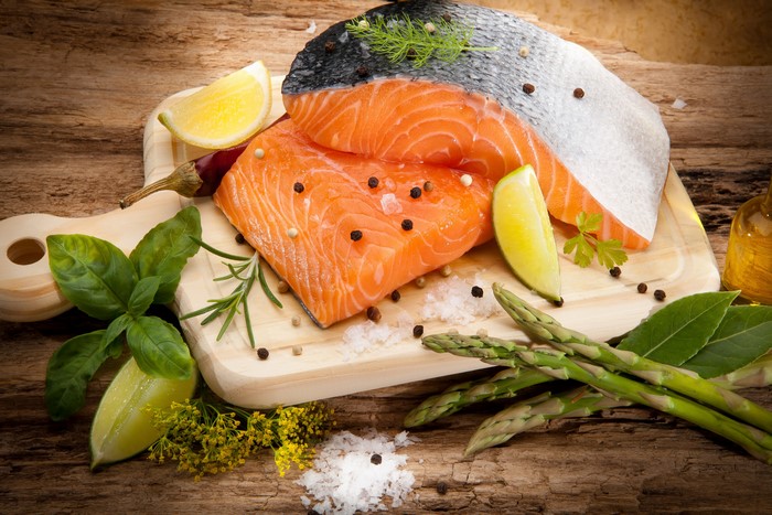 Salmon fillets with lemon, asparagus, and spices on a cutting board