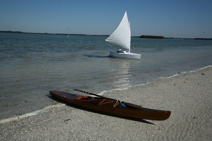 Wooden kayak and sailboat on a sandy beach