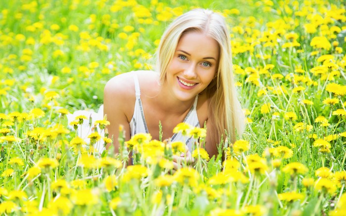 Blonde girl lying in a field of dandelions