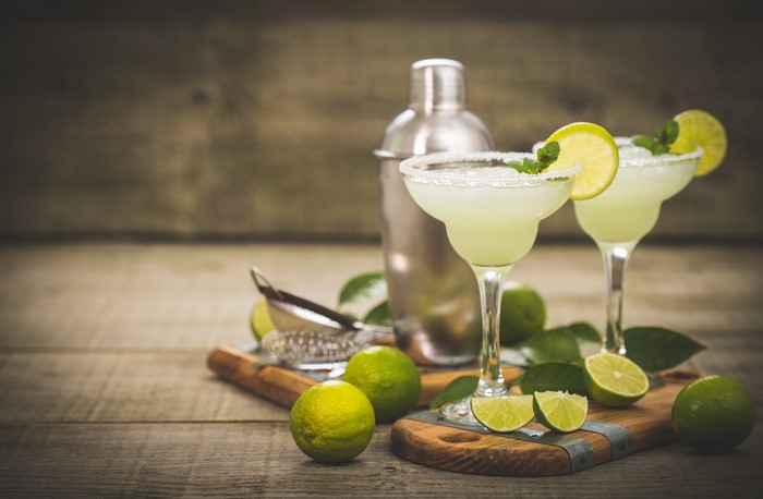 Two margaritas with limes and shaker