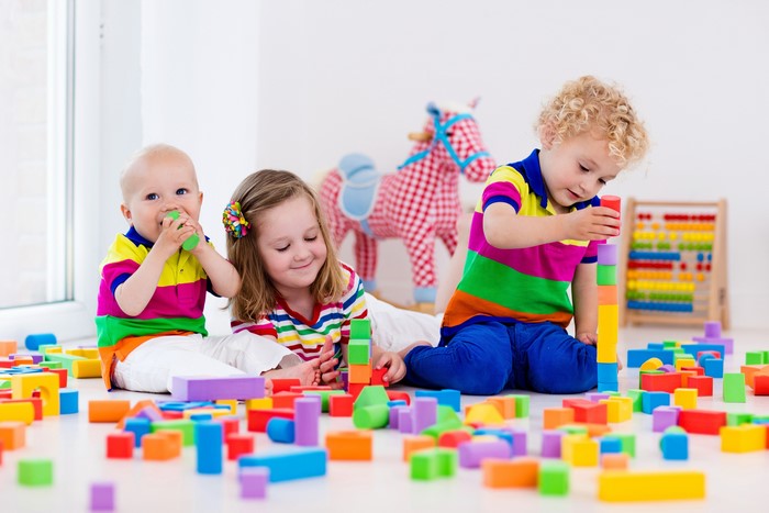 Three children playing with colorful blocks