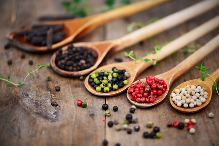 Four wooden spoons with different peppercorns