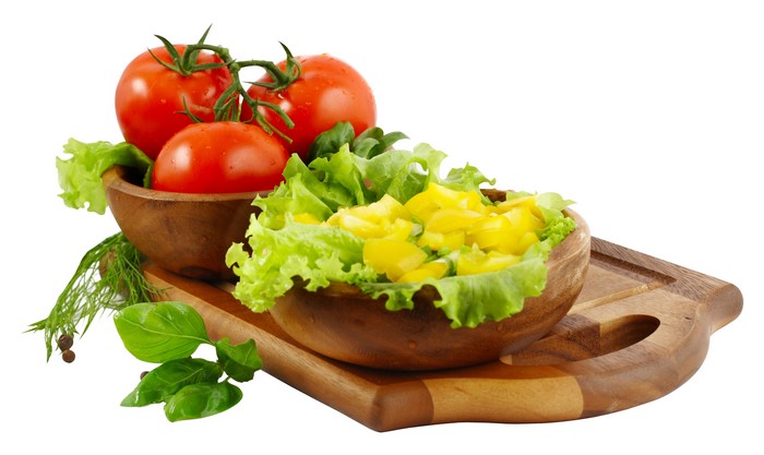 Tomatoes, lettuce, and yellow bell peppers on a cutting board