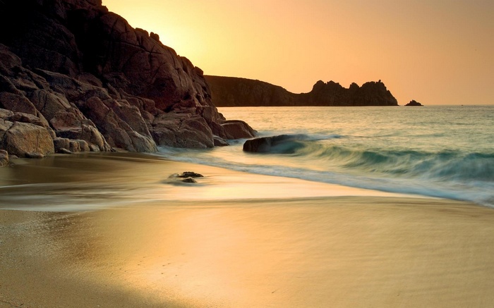 Beach with rocky cliffs and ocean at sunset