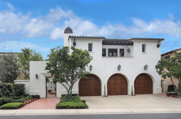 White Mediterranean-style house with arched garage doors and a courtyard gate