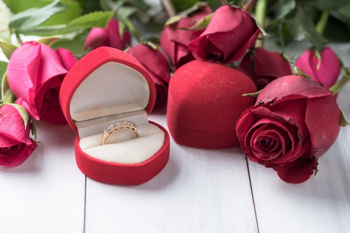 Red roses and a diamond ring in a heart-shaped box