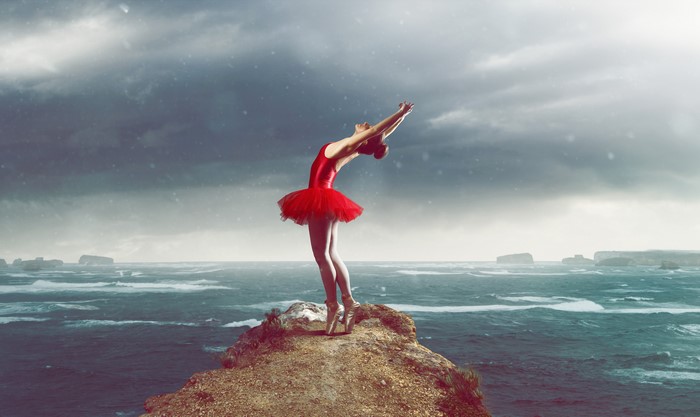 Ballerina in red tutu on a cliff by the sea