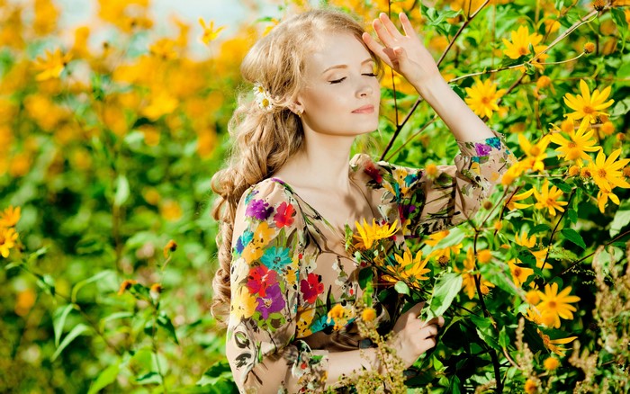 Blonde girl in a floral dress among yellow flowers