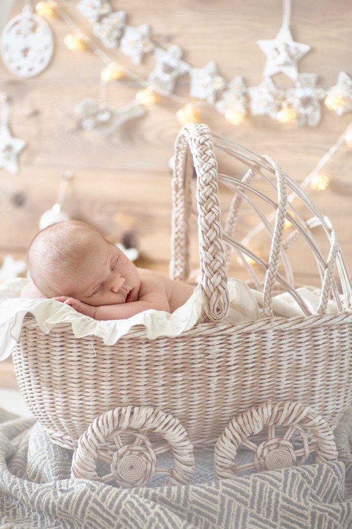 Baby sleeping in a wicker basket with Christmas lights