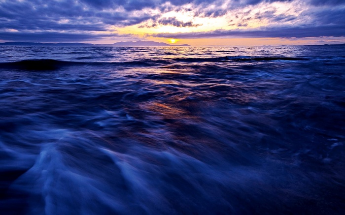 Ocean waves at sunset with distant islands