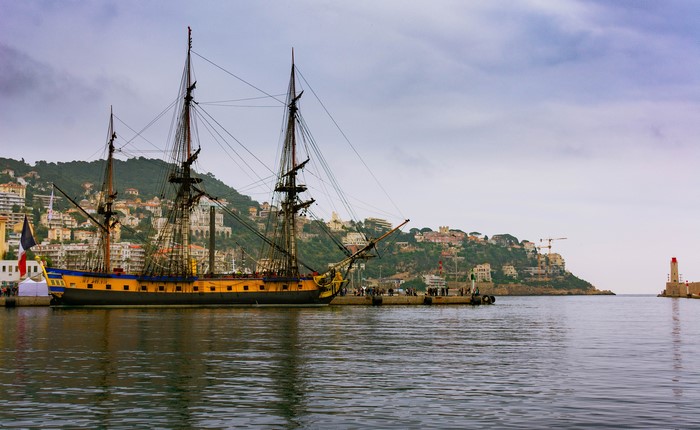 Tall ship docked in Nice, France harbor with city on hill