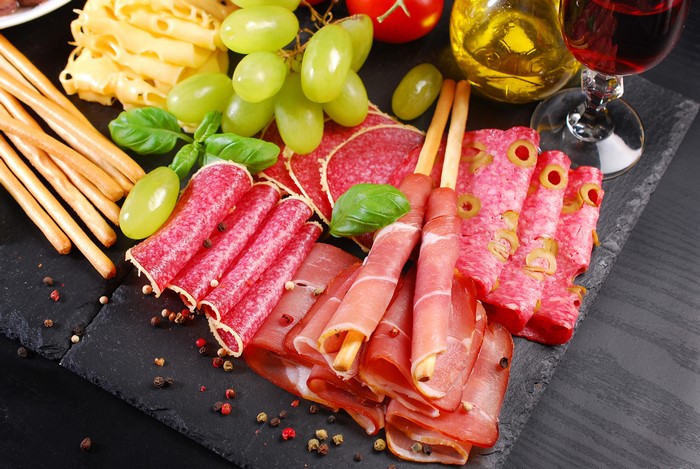 Charcuterie board with meat, cheese, grapes, and breadsticks