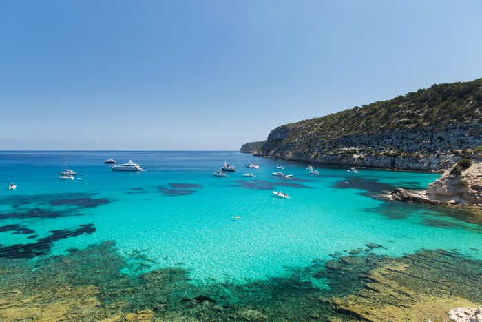 Boats in a turquoise bay on the coast of Formentera, Spain