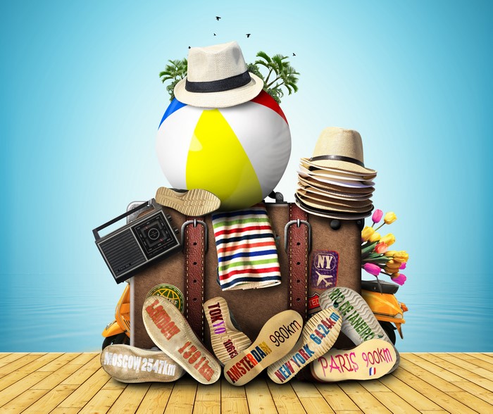 Suitcase with travel destinations and beach ball