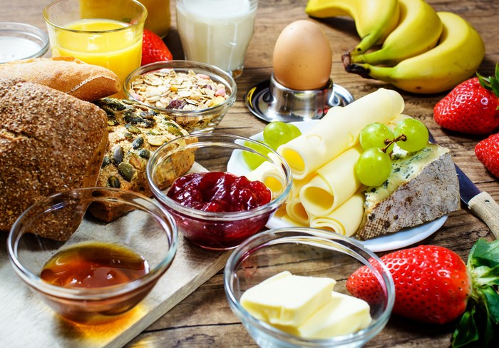 Breakfast spread with bread, cheese, fruit, and jam