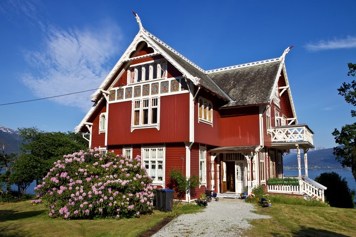 Red wooden house in Balestrand, Norway with rhododendron bush