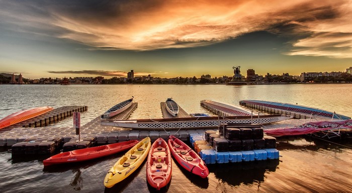Dragon boats and kayaks on a lake at sunset in Kaohsiung, Taiwan