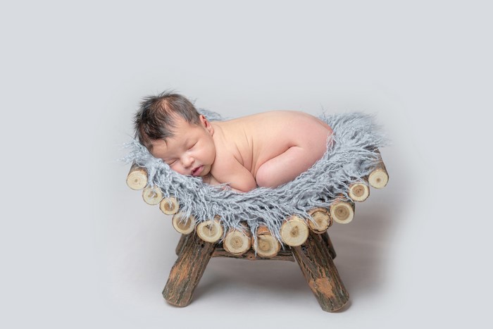 Newborn baby sleeping on a wooden prop