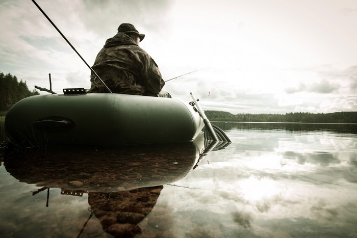 Man fishing from an inflatable boat on a lake