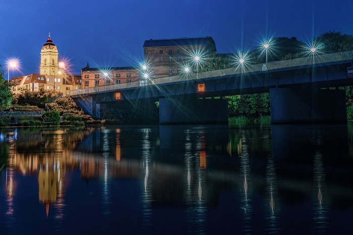 Bridge over river at night with city lights and reflections