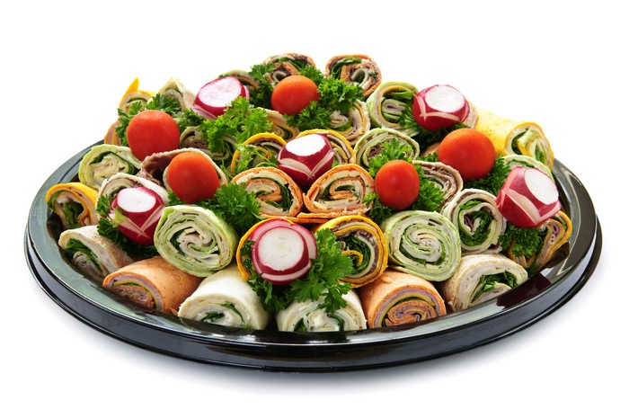Platter of assorted pinwheel wraps with tomatoes and radishes