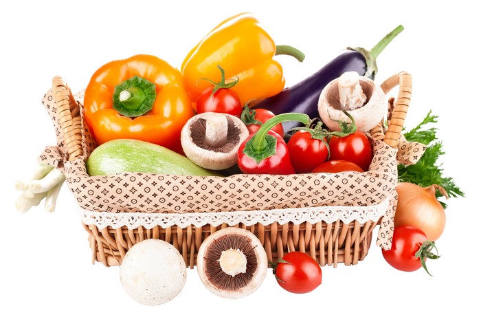 Vegetables in a wicker basket: bell peppers, mushrooms, tomatoes, eggplant, zucchini, onion, scallions