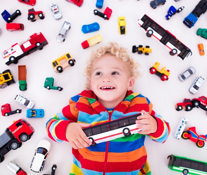 Boy playing with toy cars and bus