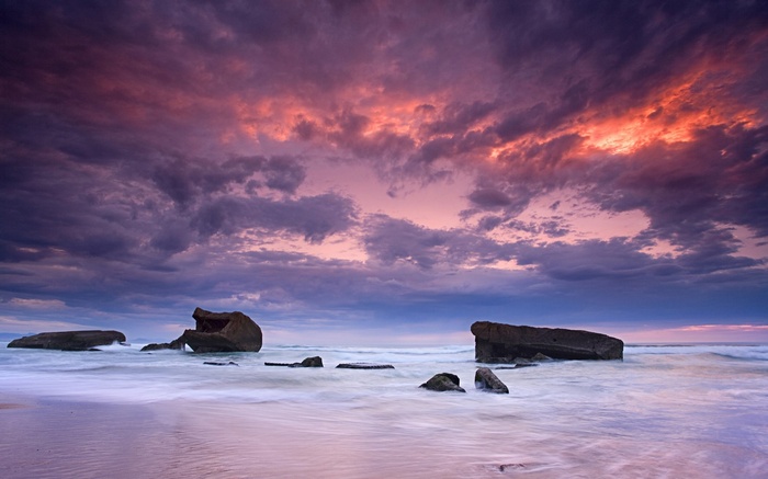 Ocean waves crash against concrete structures at sunset