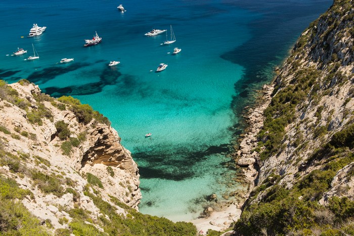 Boats in a turquoise bay near a rocky coast