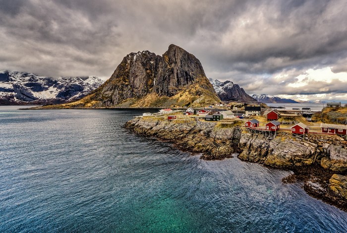 Red houses on rocky coast with mountains in Lofoten, Norway