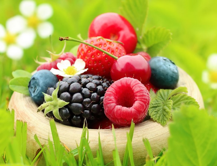 Assortment of fresh berries in a bowl on grass