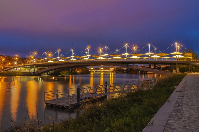 Bridge over river at night with lights reflecting on water