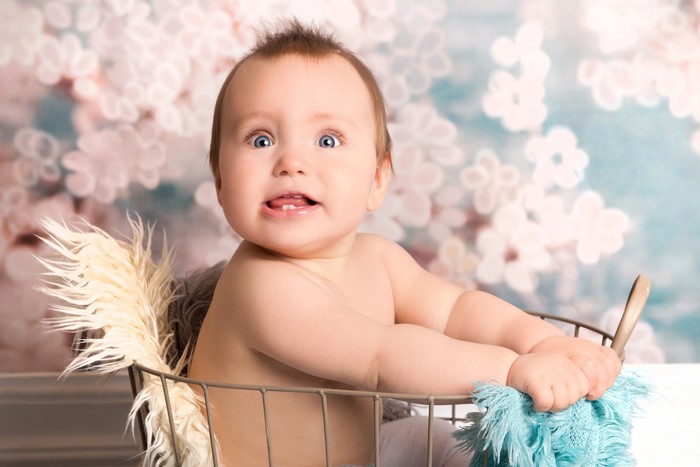 Baby sitting in a basket with a floral background