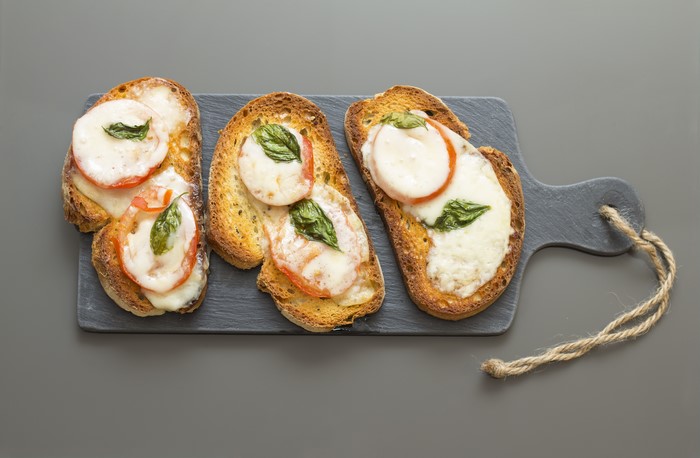 Bruschetta with tomato, mozzarella, and basil on a cutting board